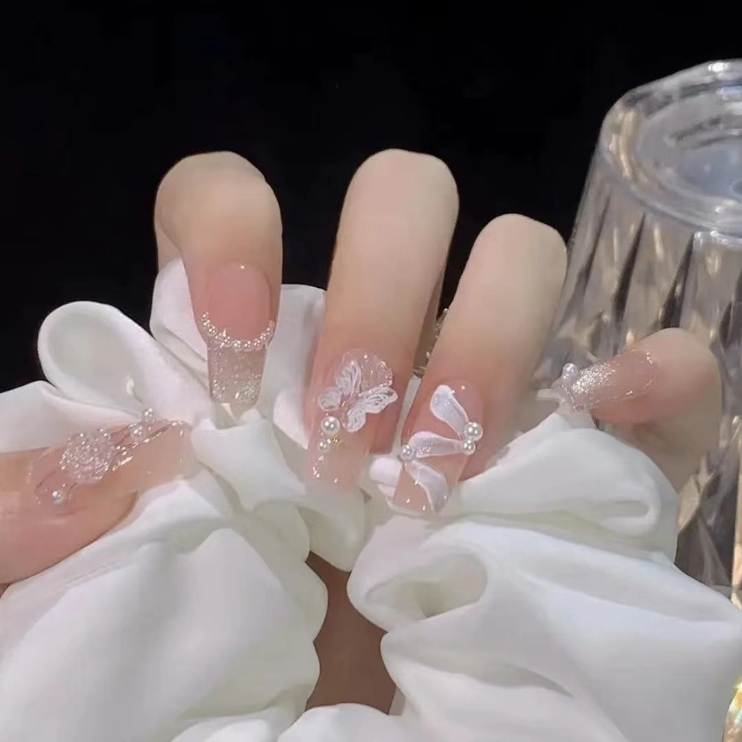 Kunstvolle Nagelkunst mit Schmetterlings- und Perlendetails Brehn