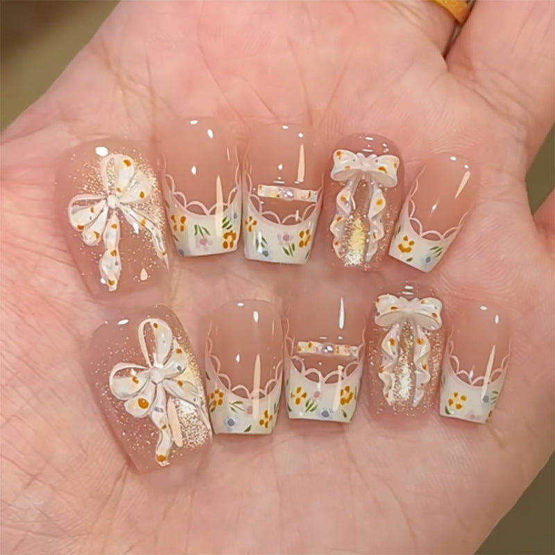 Kunstvolle Nagelverlängerungen mit floralem Design und Schleifenakzenten Brehn