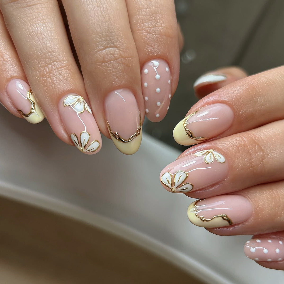 Kunstvolle Nagelverlängerungen mit floralem Design und eleganten Goldakzenten Brehn