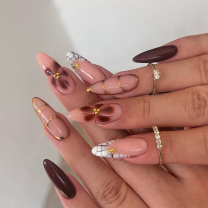 Kunstvolle Stiletto-Nägel mit Goldakzenten und dekorativen Blumenmotiven Brehn