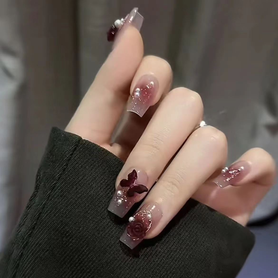Kunstvolle Nagelkunst mit Schmetterlings- und Perlendetails Brehn