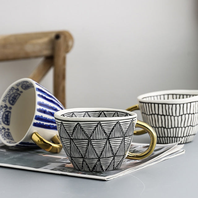 Tasse mit abstraktem geometrischen Muster und goldenem Henkel