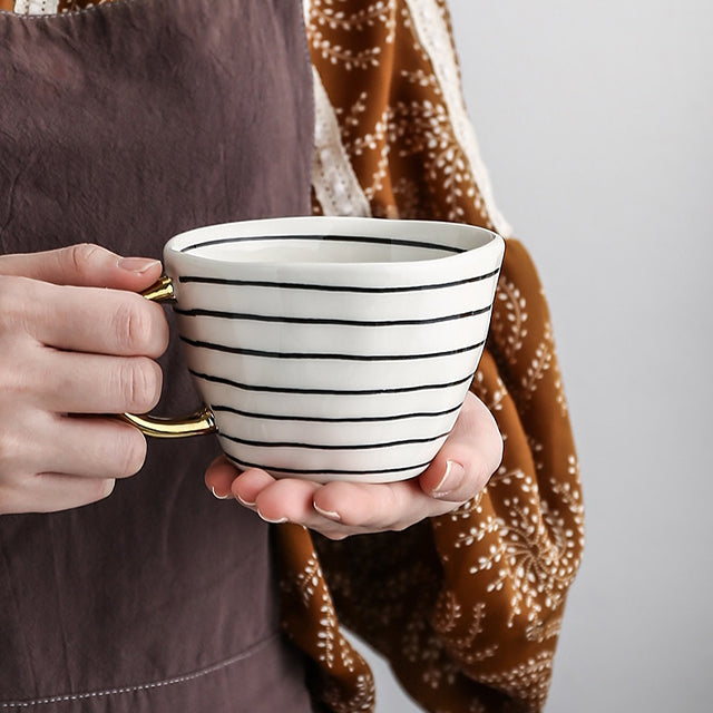 Tasse mit abstraktem geometrischen Muster und goldenem Henkel